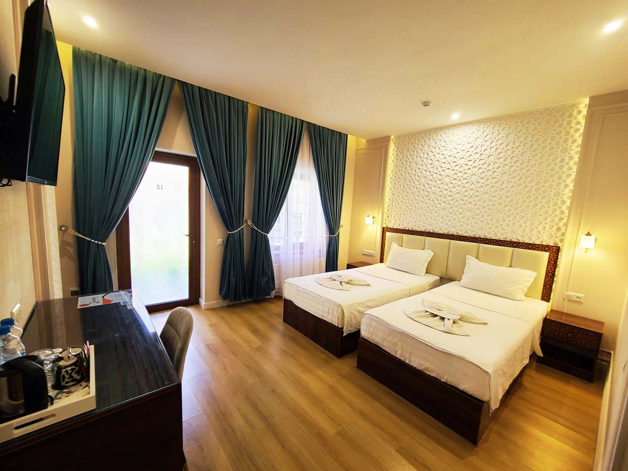 Modern hotel accommodation with twin beds, desk, and wardrobe