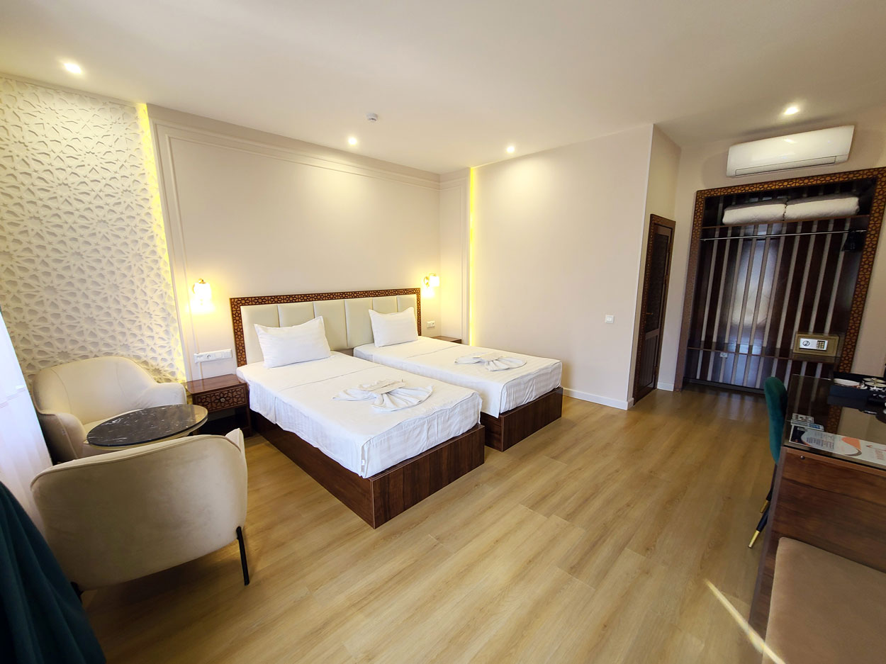 Cozy superior twin room in the hotel with twin beds, desk, coffee table, and armchairs.